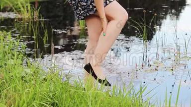 女孩站在水库附近，用双手驱赶蚊子，双手坐在她的脚上。